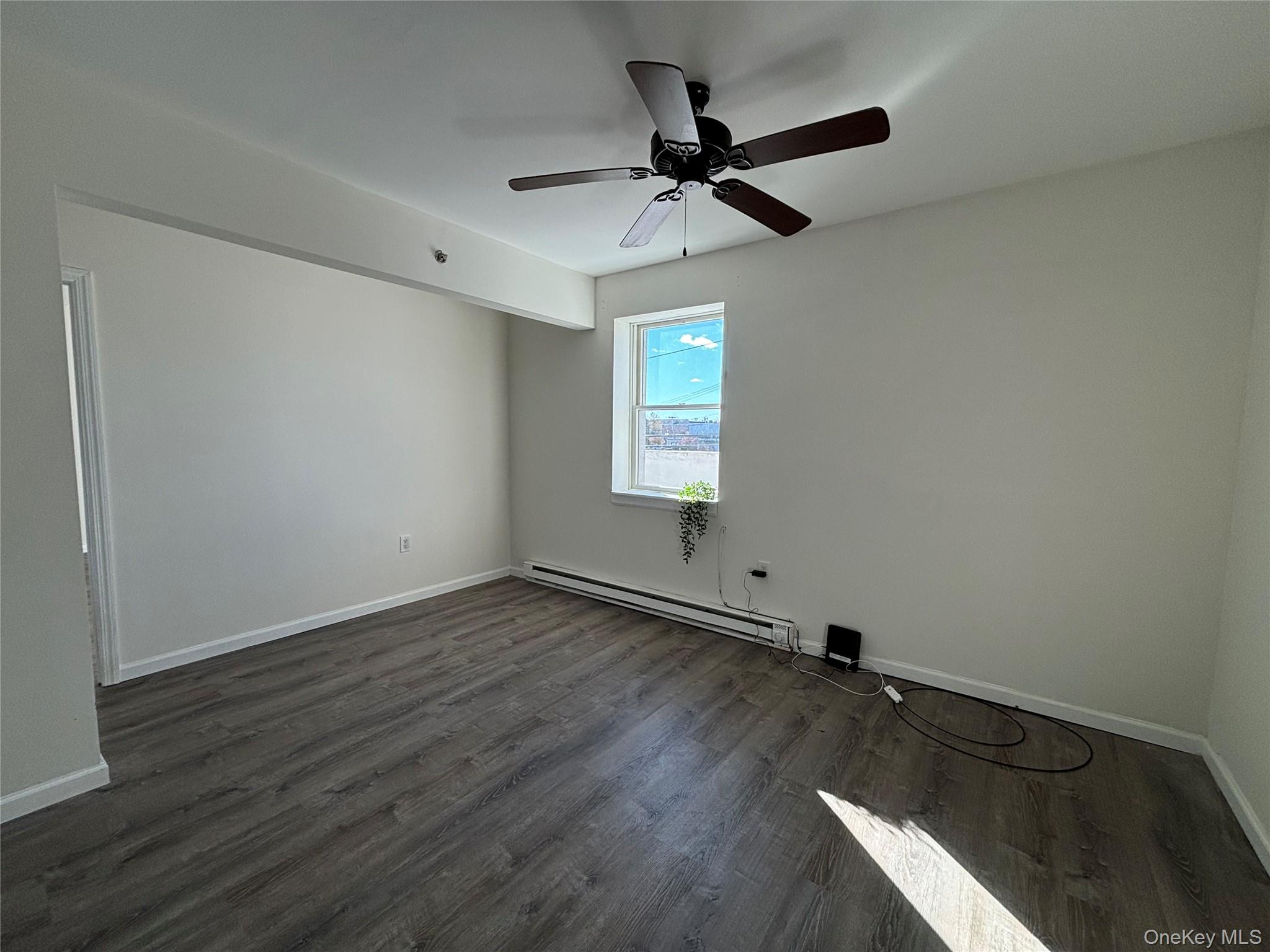 90 East Main Street, Unit 2 Patchogue, NY 11772 - Photo 4 of 14 an empty room with wooden floor fan and windows