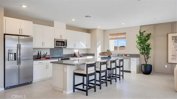 a kitchen with microwave a refrigerator and chairs