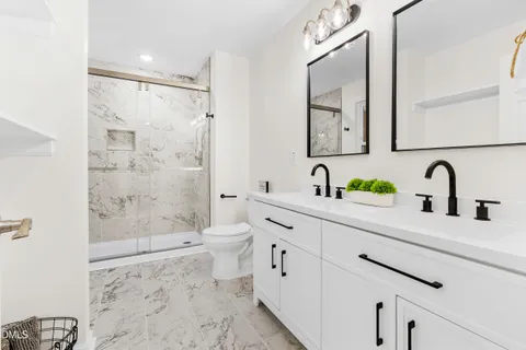 a bathroom with a double vanity sink toilet and shower