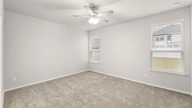 an empty room with windows and ceiling fan