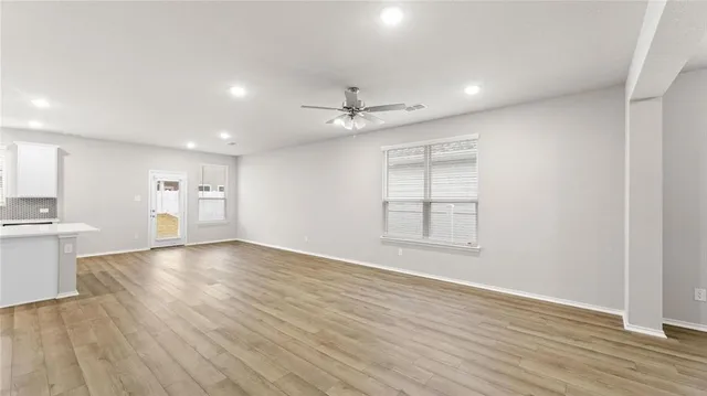 a view of an empty room with window and wooden floor