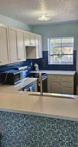 a view of a room with a large window and chandelier fan