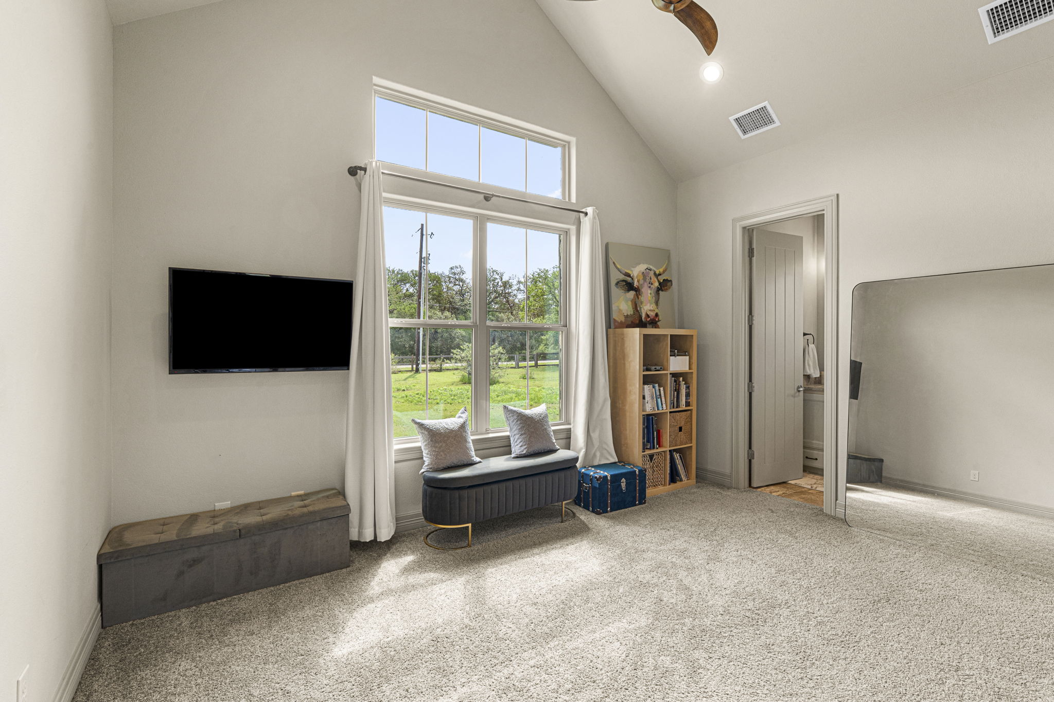 16202 Remuda Trail Buda, TX 78610 - Photo 16 of 40 Bedroom set across from primary features vaulted ceilings, light-colored carpeting, and a large window providing views of the outdoors and full bathroom ensuite