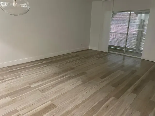 an empty room with wooden floor and mirror