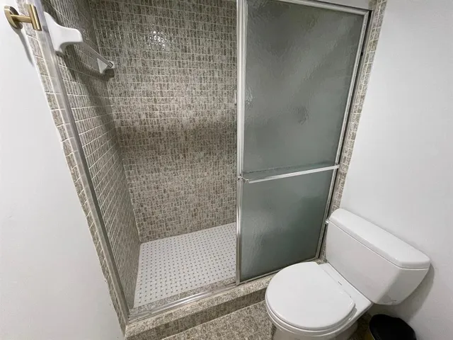 a white toilet sitting next to a shower
