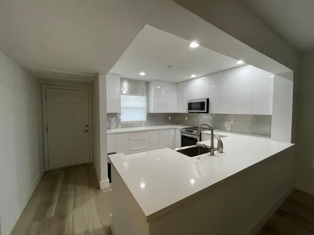a kitchen with a sink a counter top space stainless steel appliances and cabinets