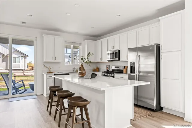 a kitchen with stainless steel appliances granite countertop a refrigerator a stove a sink dishwasher and a stove with wooden floor