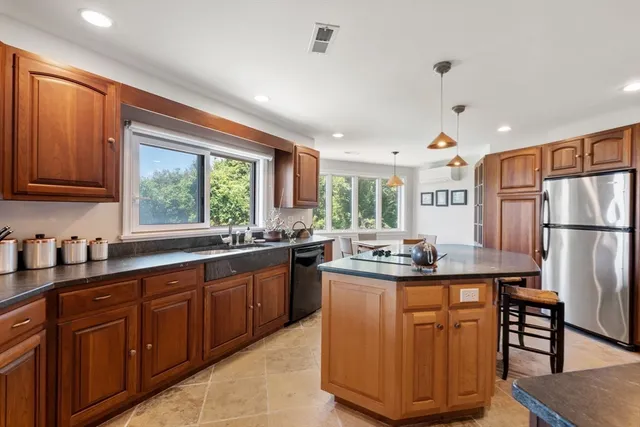 a kitchen with kitchen island granite countertop a table chairs sink and cabinets