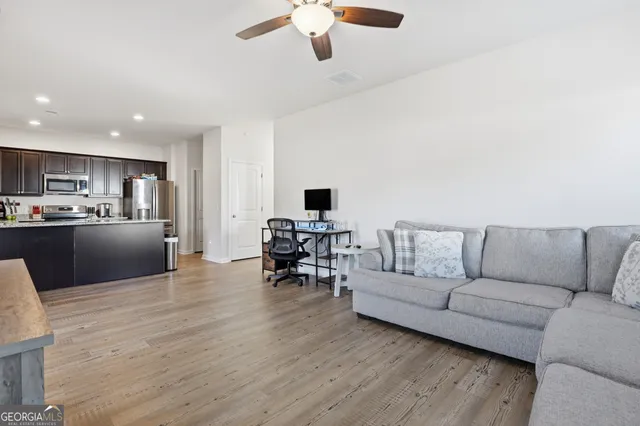 a living room with stainless steel appliances furniture and a flat screen tv