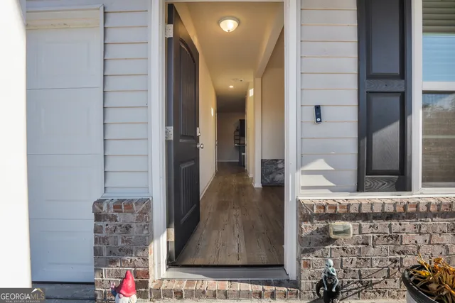a view of a hallway with wooden floor and a bathroom