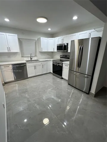 a large kitchen with stainless steel appliances a refrigerator and a sink