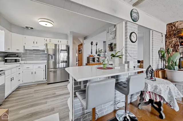 a kitchen with stainless steel appliances kitchen island a table chairs refrigerator and sink