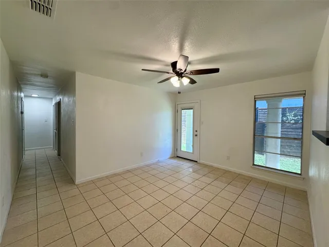 a view of an empty room with window and chandelier fan