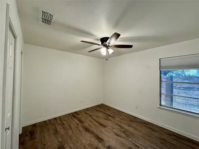 a view of empty room with wooden floor and fan