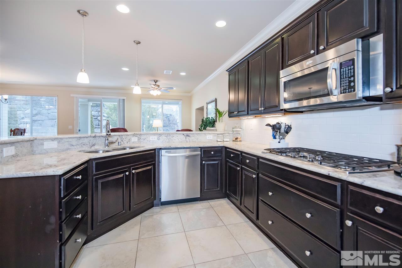 9355 Chalkstone Way Reno, NV 89523 - Photo 4 of 25 a kitchen with stainless steel appliances granite countertop a stove top oven microwave and refrigerator