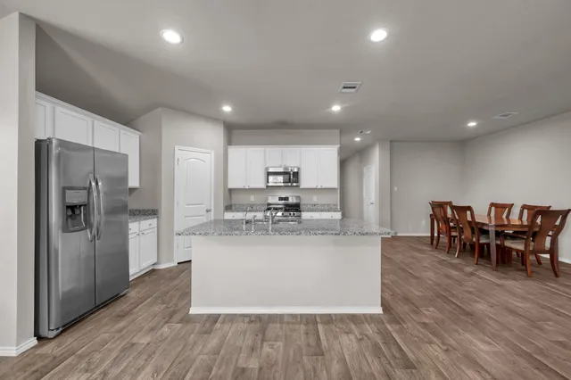 a kitchen with stainless steel appliances granite countertop a refrigerator and a stove top oven