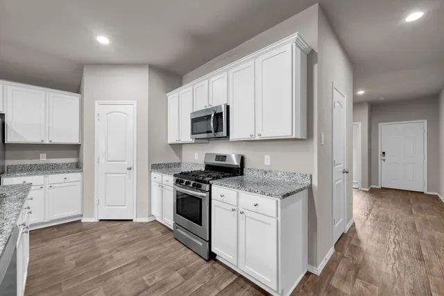 a kitchen with granite countertop white cabinets and stainless steel appliances