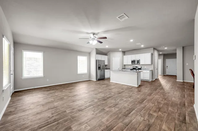 a view of an empty room with kitchen view and a window