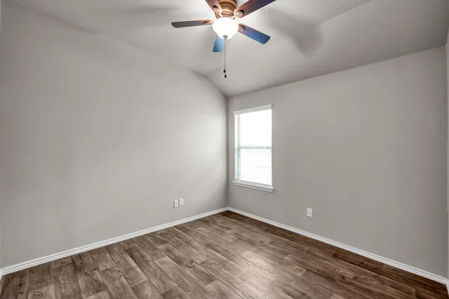 an empty room with a window and a chandelier fan