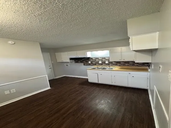 a kitchen with cabinets and wooden floor