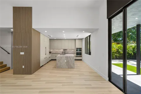 a large white kitchen with stainless steel appliances kitchen island a stove a refrigerator with white cabinets and wooden floor