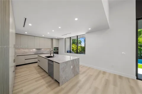 a large kitchen with granite countertop a large counter top stainless steel appliances and wooden floor