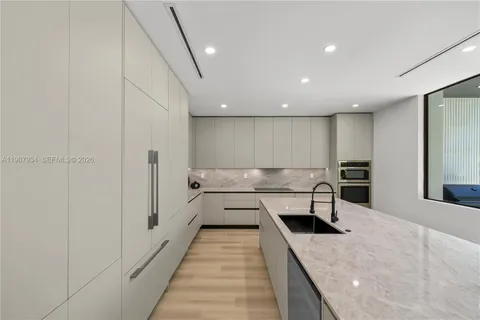 a large white kitchen with a sink and a large refrigerator
