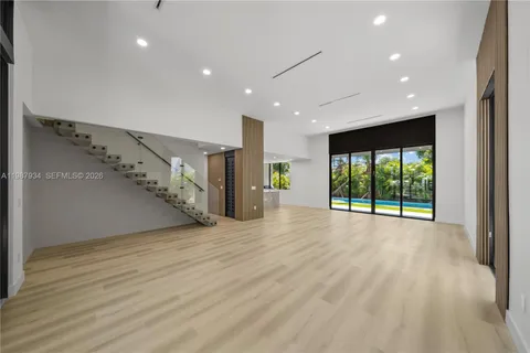 a view of an empty room with wooden floor stairs and a chandelier