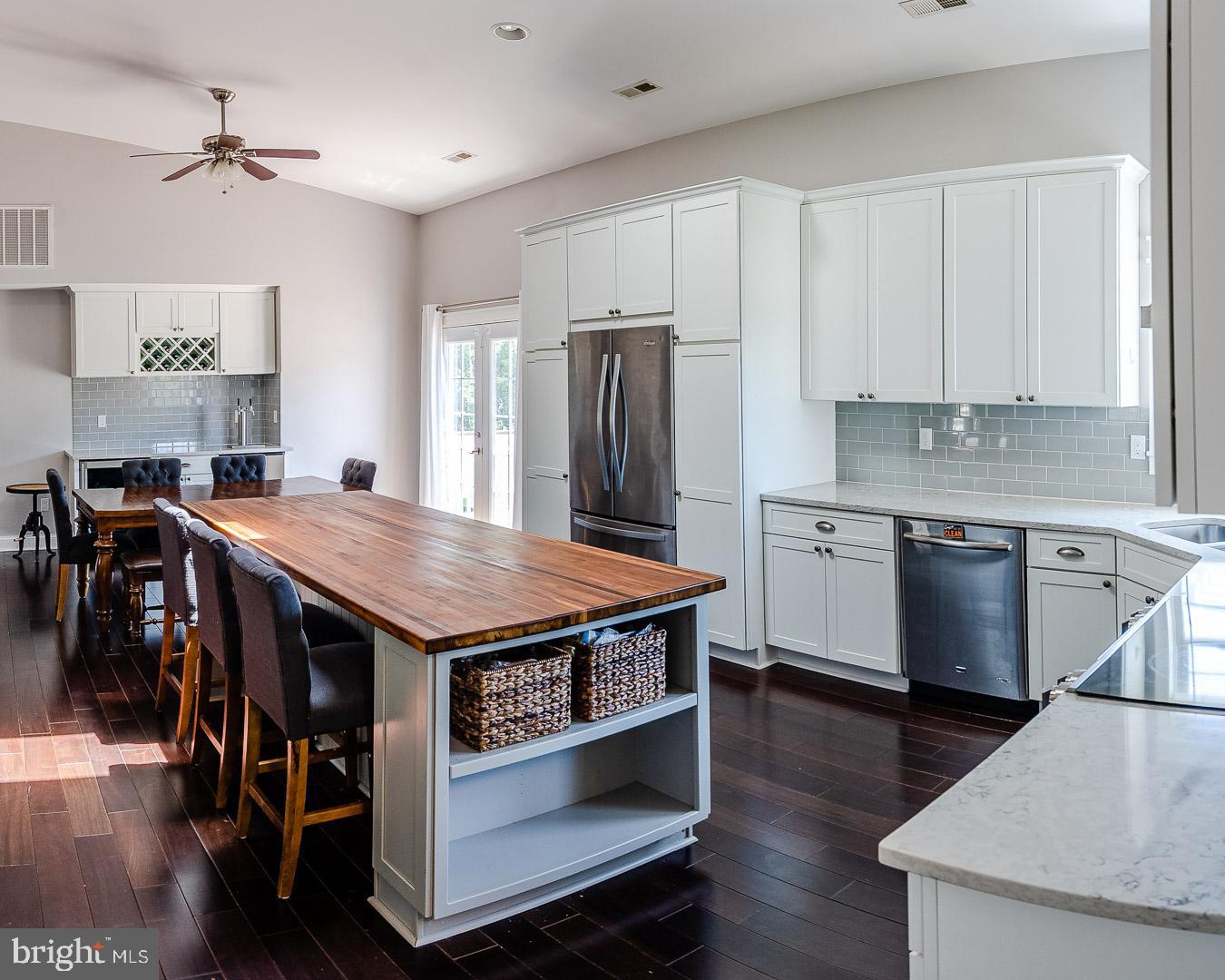 6825 Briscoe Turn Road Owings, MD 20736 - Photo 11 of 47 a kitchen with stainless steel appliances granite countertop a stove a refrigerator a sink a dining table and chairs with wooden floor