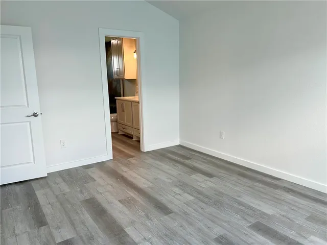 a view of an empty room with wooden floor and closet