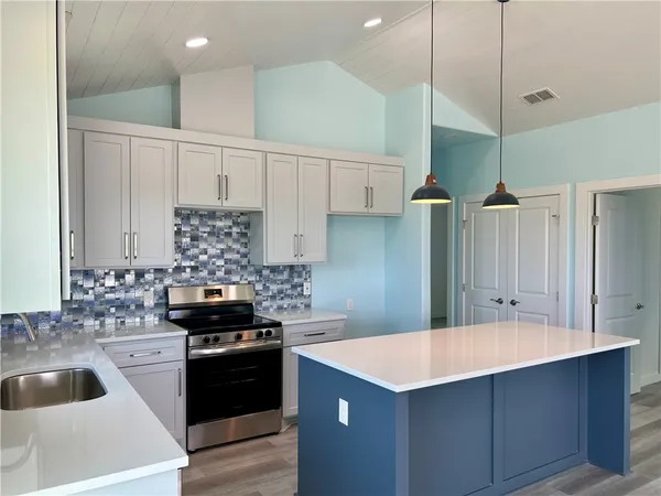 a kitchen with a sink a stove a refrigerator and white cabinets
