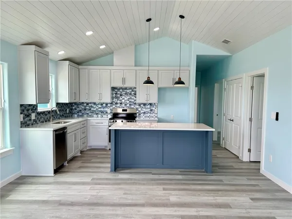 a kitchen with stainless steel appliances kitchen island granite countertop a stove a sink and a refrigerator