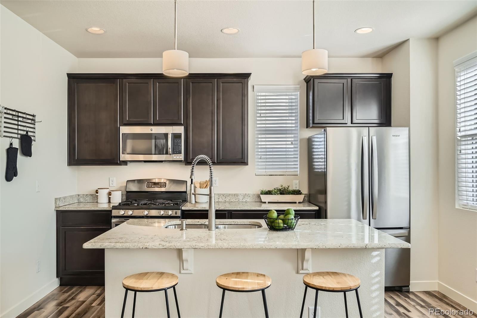 11225 Colony Circle Broomfield, CO 80021 - Photo 2 of 25 a kitchen with stainless steel appliances granite countertop a sink a microwave a refrigerator and chairs