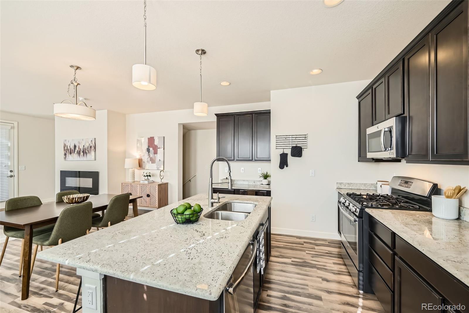 11225 Colony Circle Broomfield, CO 80021 - Photo 4 of 25 a kitchen with granite countertop cabinets a stove a sink a dining table and chairs