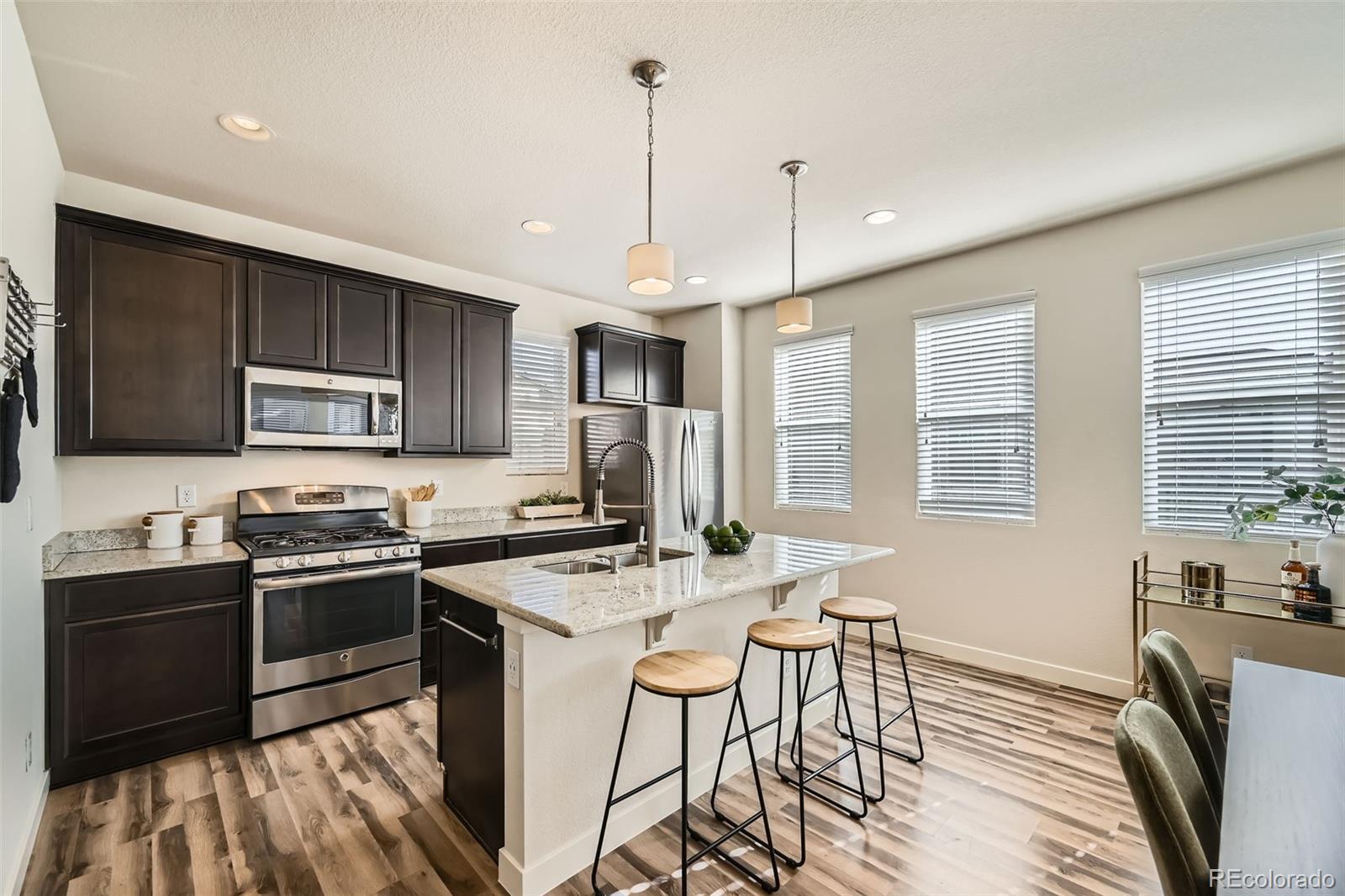 11225 Colony Circle Broomfield, CO 80021 - Photo 5 of 25 a kitchen that has a sink a stove top oven a refrigerator cabinets and a dining table with chairs