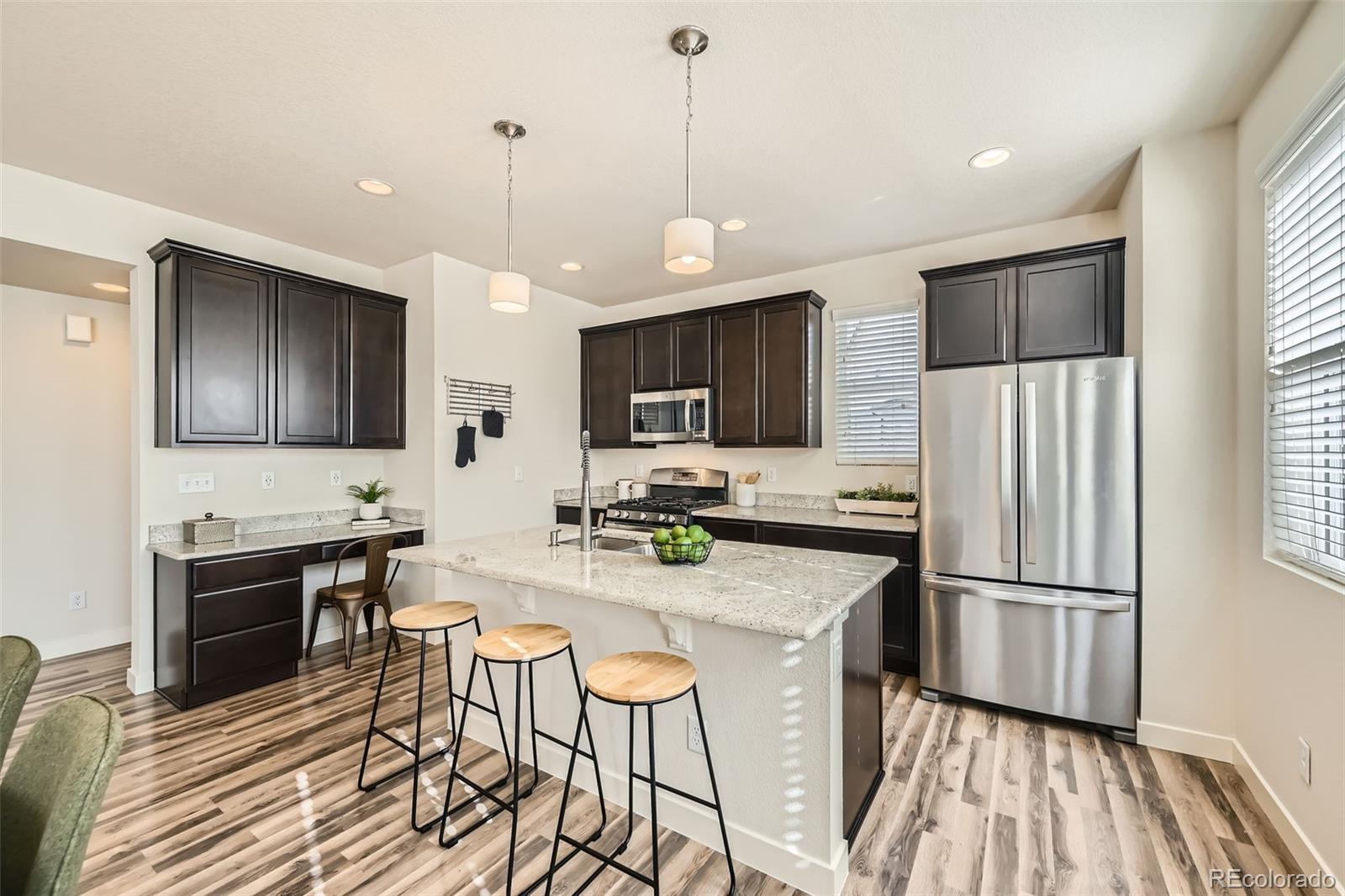 11225 Colony Circle Broomfield, CO 80021 - Photo 6 of 25 a kitchen with stainless steel appliances granite countertop a refrigerator a stove top oven a sink dishwasher a dining table and chairs with wooden floor