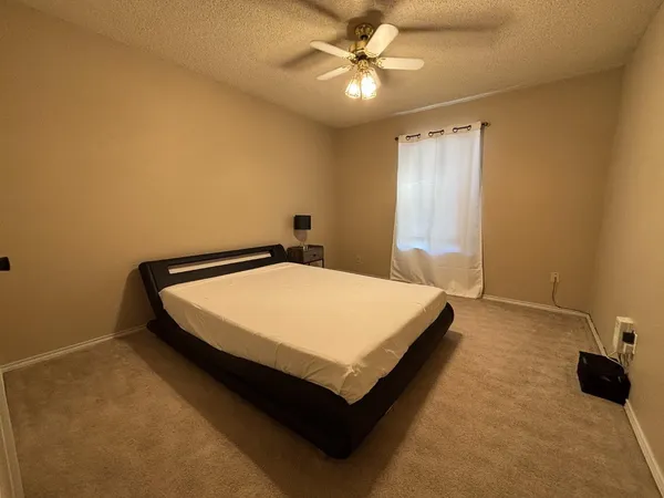 a bed sitting in a spacious bedroom next to a window