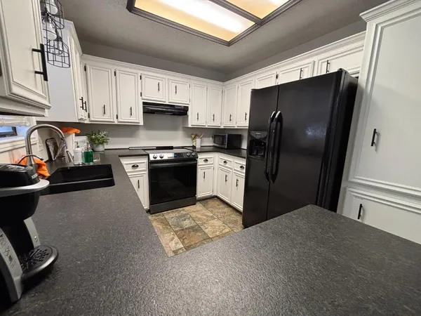 a kitchen with stainless steel appliances granite countertop a stove top oven a refrigerator and white cabinets