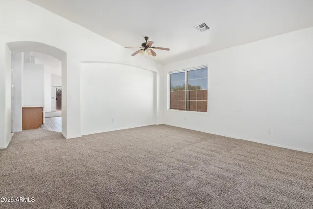 an empty room with windows and ceiling fan