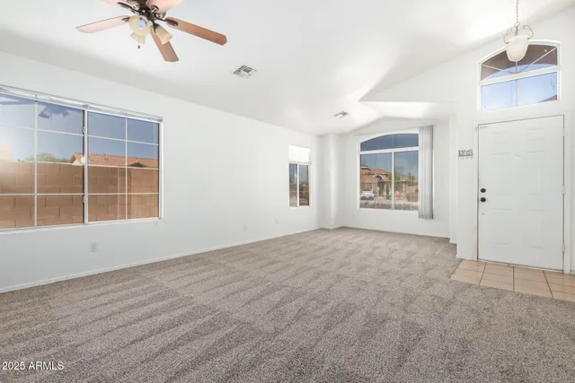 an empty room with windows and fan