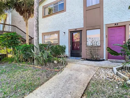 a view of a brick house with many windows plants and large tree
