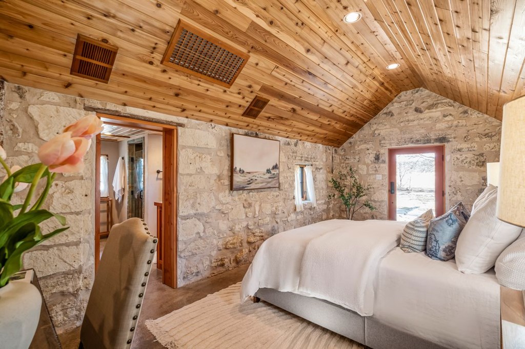 9402 Doss-Spring Creek Road Doss, TX 78618 - Photo 43 of 78 a spacious bedroom with a bed and wooden floor