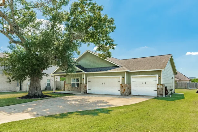a view of a yard in front of a house with a large tree