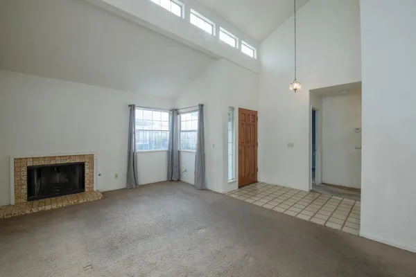 an empty room with windows and fireplace
