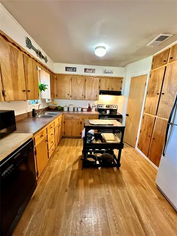 a kitchen with a sink a stove a refrigerator cabinets and a dining table