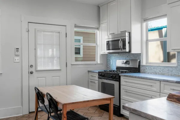 a kitchen with a table chairs microwave and cabinets
