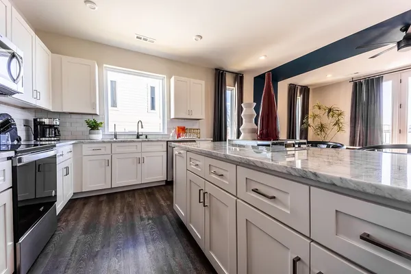 a kitchen with stainless steel appliances granite countertop a stove top oven a sink dishwasher and a refrigerator with wooden floor