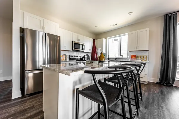 a kitchen with stainless steel appliances granite countertop a refrigerator a sink dishwasher a oven with white cabinets and wooden floor