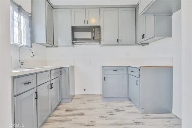 a kitchen with white cabinets and sink