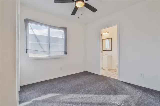 an empty room with chandelier fan and windows